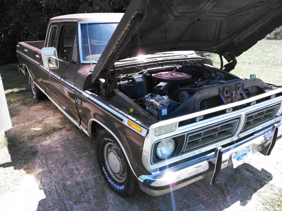 Brown Ford pickup truck, hood open showing engine. Front grille has 'FORD' lettering
