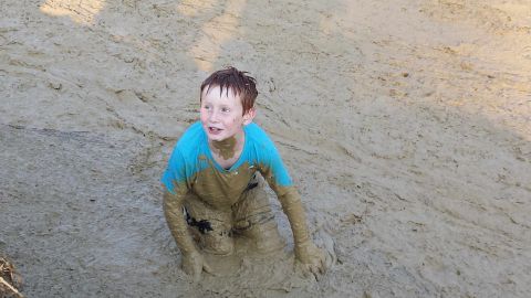 1987 Ford Bronco - Young boy emerges from a mud pit, covered head to toe.