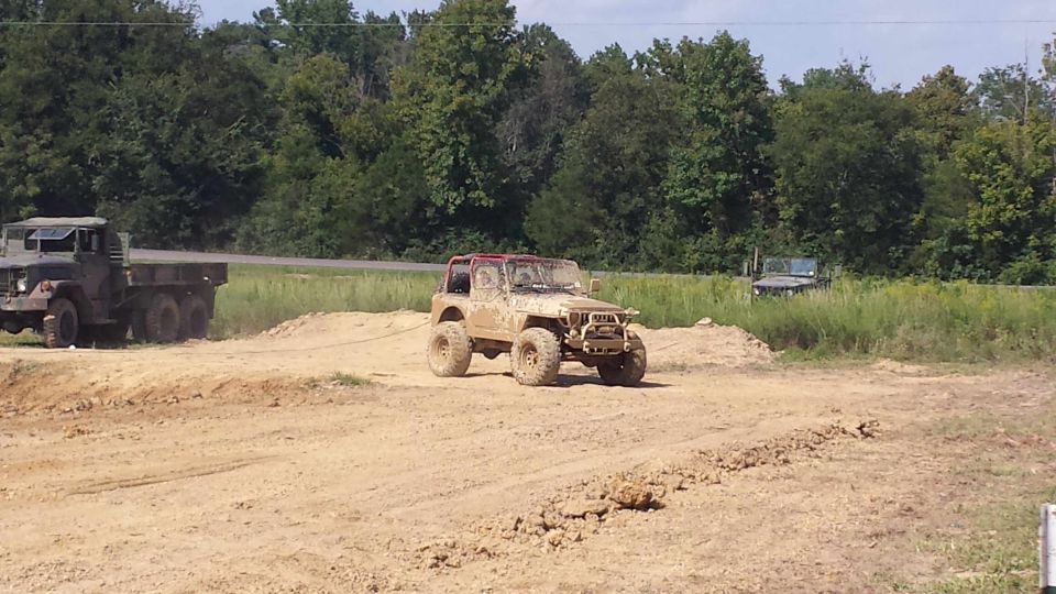 Muddy off-road vehicle being towed by a military truck