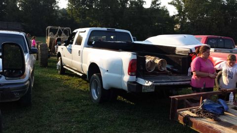 1987 Ford Bronco - A white pickup truck is parked outdoors with its tailgate open, revealing cargo in the bed.