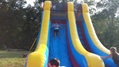 1987 Ford Bronco - A boy slides down a large inflatable structure while others watch.