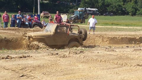 1987 Ford Bronco - Mud bogging event with a Jeep Wrangler struggling through a deep mud pit.