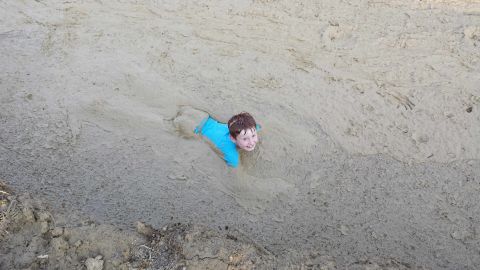 1987 Ford Bronco - A child is submerged in mud, with only their head and shoulders visible.