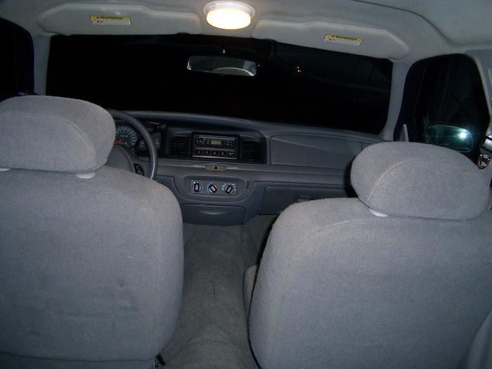 Rear-seat view of gray cloth interior, dashboard, radio and steering wheel at night