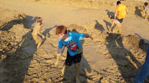 1987 Ford Bronco - Children play in a muddy pit, with one child in the foreground wearing a blue shirt.