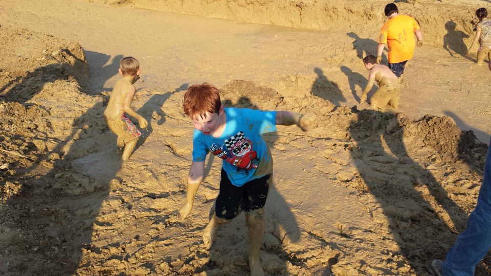 Children covered in mud playing in a muddy pit