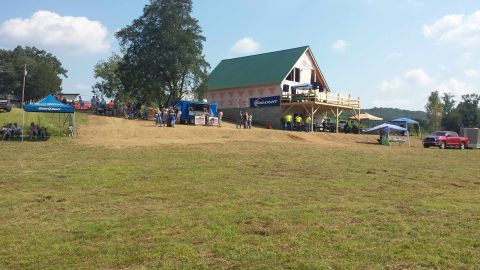 1987 Ford Bronco - A red pickup truck is visible in the distance at an outdoor event with a building under construction.