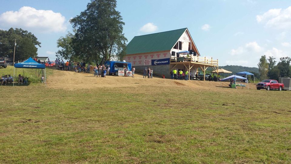 Red pickup truck parked on a grassy field near a building under construction