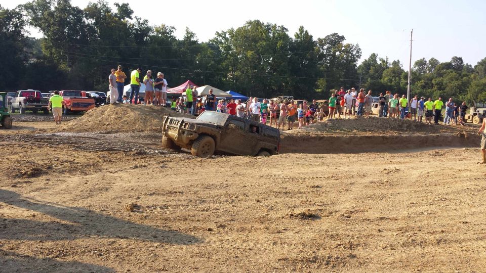 Muddy SUV stuck in a ditch with people watching