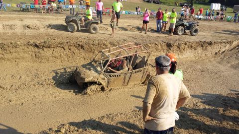 1987 Ford Bronco - Spectators observe an off-road vehicle struggling in a mud bog during an event.