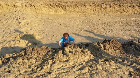 1987 Ford Bronco - A child plays in a sandy ditch, with the Supermotors logo visible in the lower right corner.