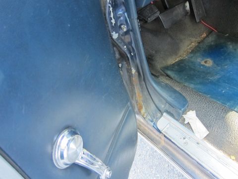 2001 Ford Crown Victoria - Interior view of a car door, showing the door panel, window crank, and rusted door jamb.