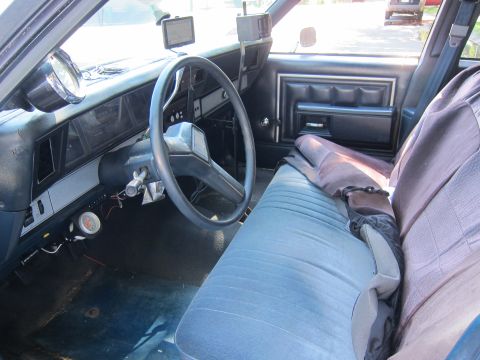 2001 Ford Crown Victoria - The interior of a car shows blue patterned seats, a steering wheel, and dashboard details.
