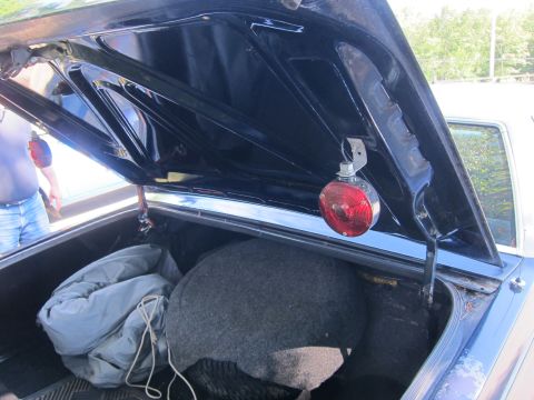 2001 Ford Crown Victoria - The interior of a car's trunk is shown, containing a spare tire, a covered item, and a red light attached to the trunk lid.