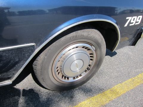 2001 Ford Crown Victoria - A portion of a dark blue sedan is shown, focusing on the rear wheel and a numerical marking on its body.