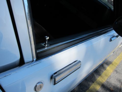 2001 Ford Crown Victoria - Close-up of a white car door's interior lock and handle assembly.