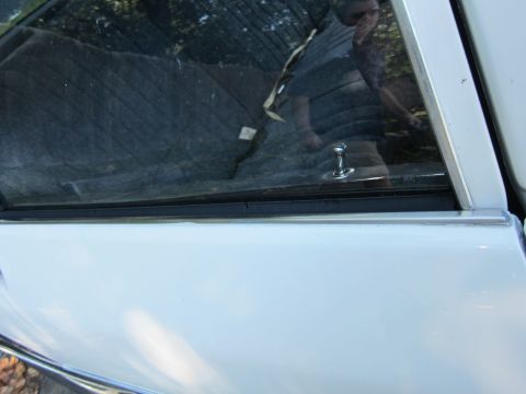 2001 Ford Crown Victoria - Close-up of a white car's side door and window, showing a reflection of a person in the glass.