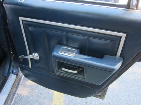 2001 Ford Crown Victoria - Close-up of a car's interior door panel, showing the armrest and window crank.