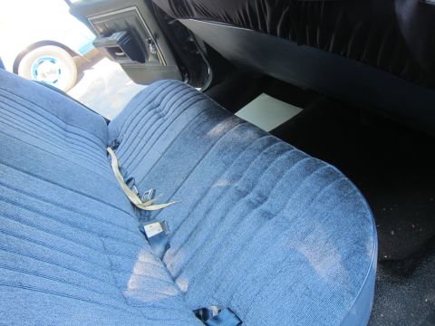 2001 Ford Crown Victoria - The interior of a car shows blue velour seats and a door panel, with another vehicle visible through the window.