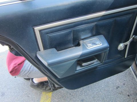 2001 Ford Crown Victoria - Close-up of a car's interior door panel, showing the armrest, door handle, and window crank.
