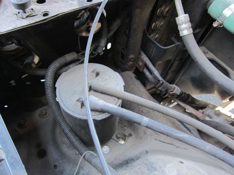 2001 Ford Crown Victoria - Close-up view of various hoses and a cylindrical component within a vehicle's engine bay.