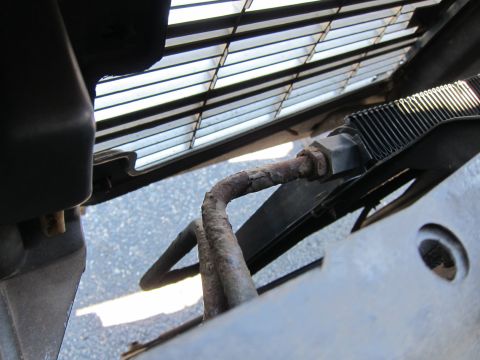 2001 Ford Crown Victoria - A close-up view of a corroded metal pipe and part of a vehicle's grille.