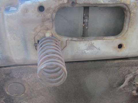 2001 Ford Crown Victoria - The internal workings of a car door's latch system are visible, showing a spring and metal rod.