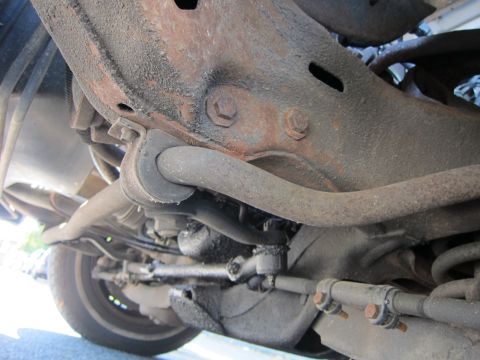 2001 Ford Crown Victoria - Close-up view of the undercarriage, showing suspension components and a tire, with visible rust and grime.