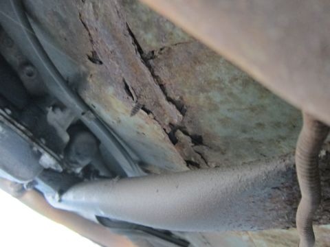 2001 Ford Crown Victoria - Significant corrosion is visible on the vehicle's frame rail, indicating structural compromise.