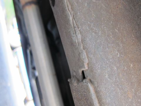 2001 Ford Crown Victoria - Close-up view of a rusted metal frame and exhaust pipe, likely from a vehicle's undercarriage.