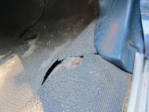 2001 Ford Crown Victoria - The floor mat in this vehicle is torn, revealing rust on the metal beneath.