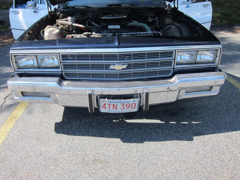 2001 Ford Crown Victoria - The front of a black Chevrolet Caprice is shown with its hood open, revealing the engine compartment.