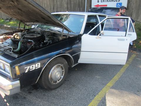 2001 Ford Crown Victoria - Photo of a Chevrolet Caprice police cruiser numbered 799 with hood up, not a technical document.