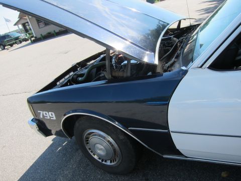 2001 Ford Crown Victoria - Photograph of a classic sedan's front fender and open hood, not a document.