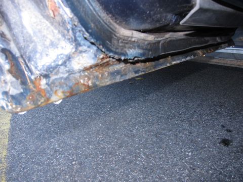 2001 Ford Crown Victoria - Photograph of a rusted car rocker panel, not a technical document.
