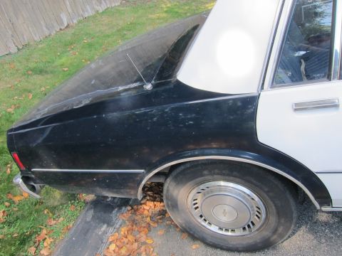 2001 Ford Crown Victoria - A black and white police car is parked outdoors with its hood up, showing the engine compartment.