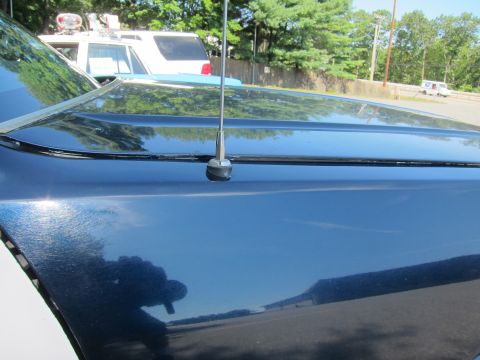 2001 Ford Crown Victoria - Close-up view of a dark blue car's hood, a prominent antenna. Another vehicle is partially visible in the background.