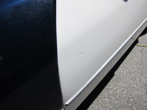 2001 Ford Crown Victoria - Close-up of a car door showing a scratch on the silver section, adjacent to a black section.