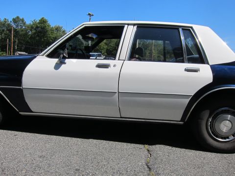 2001 Ford Crown Victoria - This two-tone vehicle appears to be a police car, but its specific make and model are not identifiable from this side profile.