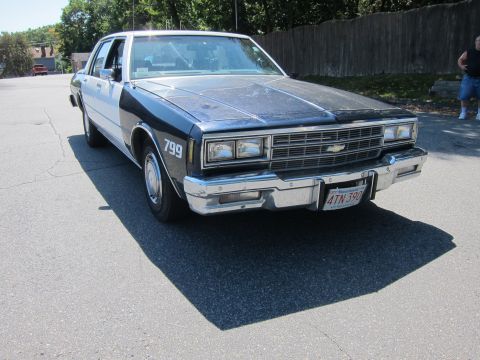 2001 Ford Crown Victoria - A dark blue and white sedan, resembling a police vehicle, is parked on an asphalt surface.