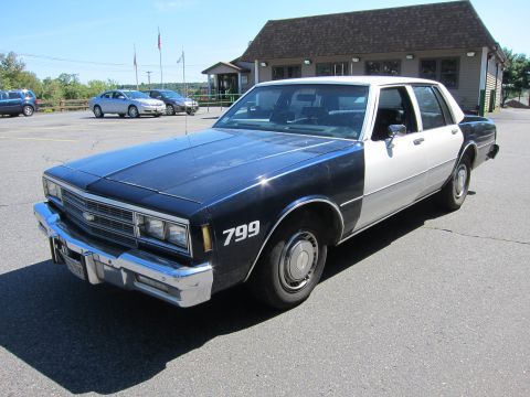 2001 Ford Crown Victoria - This two-tone sedan appears to be a former police vehicle, marked with the number 799.