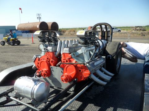 1973 Ford Ranchero - A dragster with twin V8 engines is prepared for an event, with a person attending to the rear tire.