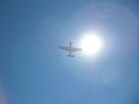 1973 Ford Ranchero - An airplane is seen flying against a bright sun in the sky.