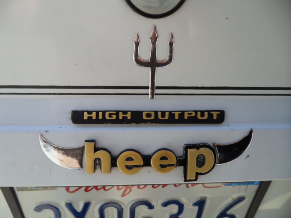 Rear of a white vehicle with a trident emblem, 'HIGH OUTPUT' badge, and 'heep' lettering with horns