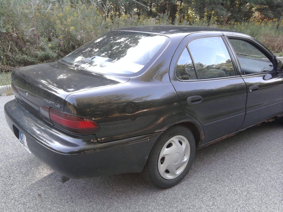 Dark sedan, rear view. Appears to be a 1995 Geo Metro