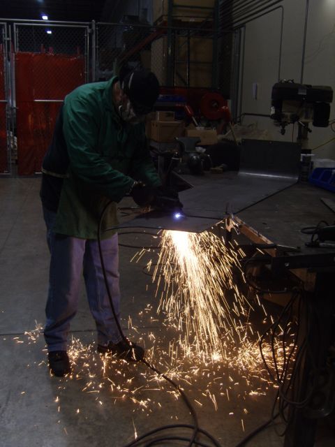 1985 Jeep CJ7 - Workshop scene with a person using a plasma cutter on a metal sheet.