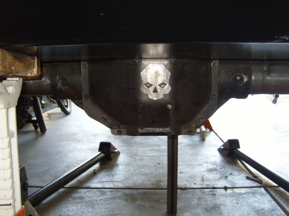 Custom differential cover with a skull emblem welded on. Vehicle is on jack stands