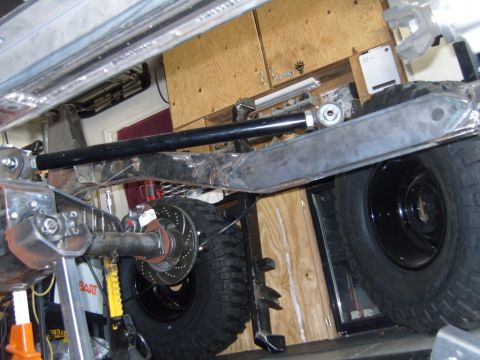 1985 Jeep CJ7 - Close-up view of the undercarriage and suspension system of a Jeep, with large off-road tires visible.