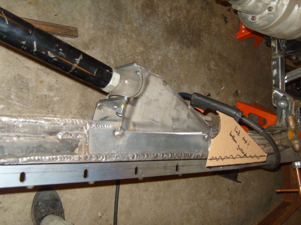 Custom suspension link mount being welded onto a frame rail. Cardboard template with notes is attached