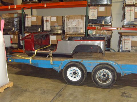 1985 Jeep CJ7 - Jeep CJ body panels are strapped to a trailer in a warehouse setting.